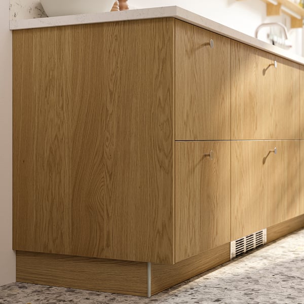 Wooden kitchen cabinet in oak colour, featuring subtle grain patterns, installed against a wall with multiple drawers.