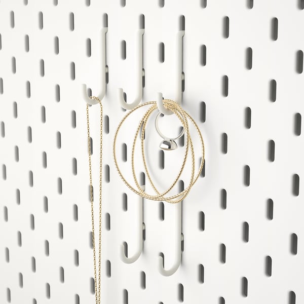White pegboard with hooks holding gold chain items, ideal for organising accessories like jewellery or keys.