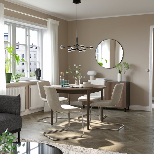 Modern dining setup with extendable 4-seat table and cantilever chairs, plants, and sheer curtains.