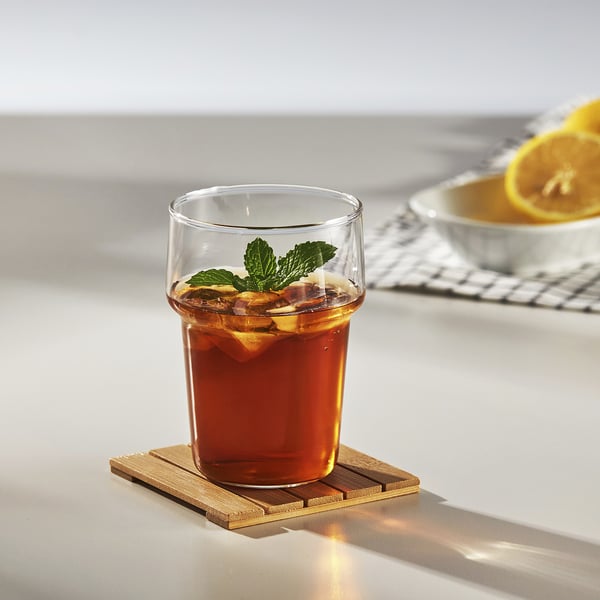 Glass cup with iced tea & mint on bamboo coaster.