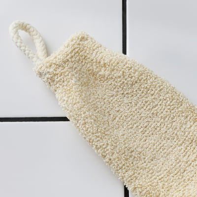 Cream-colored crocheted scrub mitt with textured cotton yarn, featuring a thick braided loop for hanging, displayed on a minimalist background.