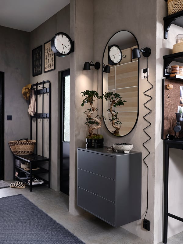 Modern entryway with black furniture, hats, storage, mirror, lamps, and curved wall decor.
