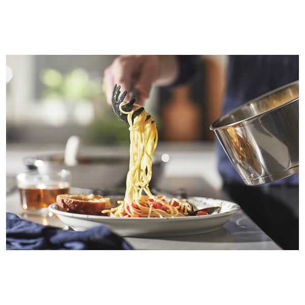 Person serving spaghetti on a table with blue napkin.