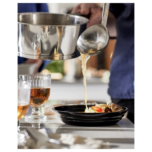 Chef pouring sauce into bowl, glass beside.
