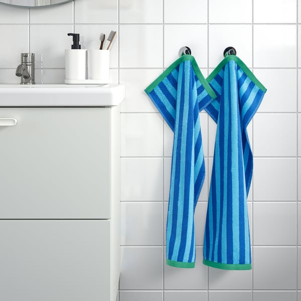 Blue-striped towels hang on hook beside sink and cabinet.