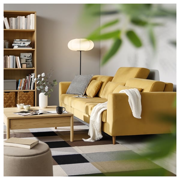 Cosy living room with yellow SLATORP sofa, wooden coffee table, bookshelf, lamp, plant, and chequered rug.