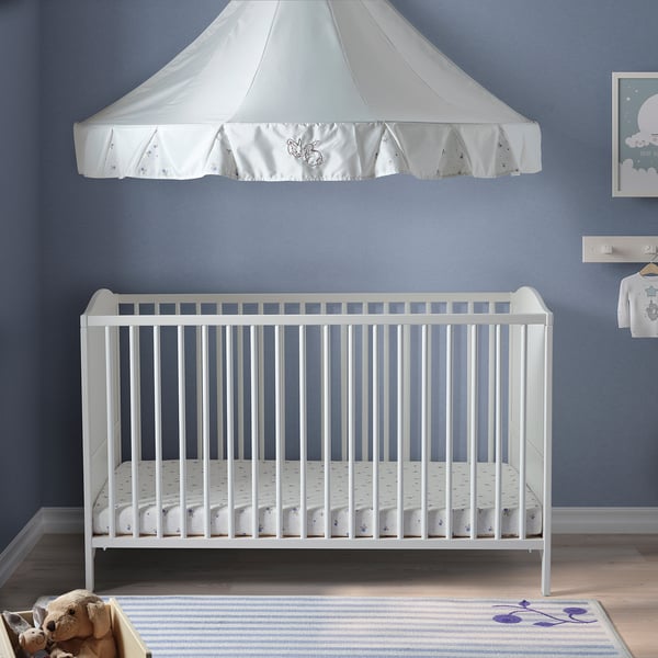 White SMÅGÖRA crib with light blue canopy, safe & comfy design in a blue room.