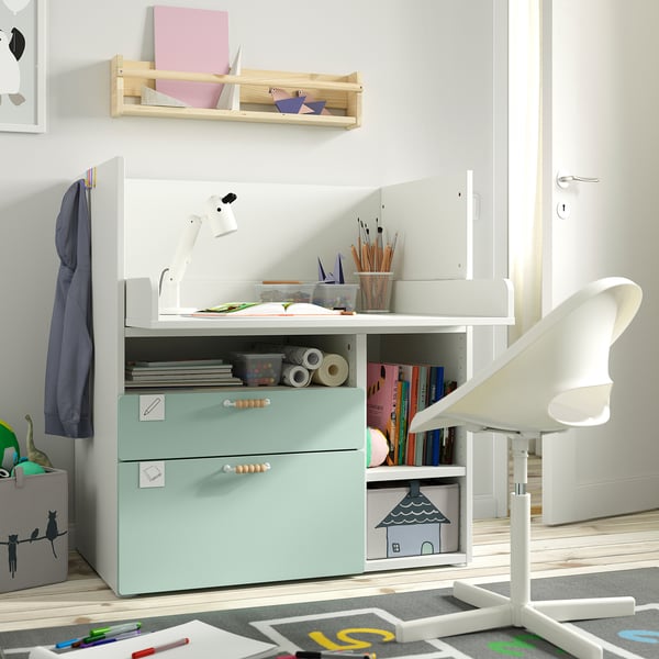 Kids workspace with SMÅSTAD mint desk, white chair, wooden shelves, art supplies, books, coat hook, and rug.