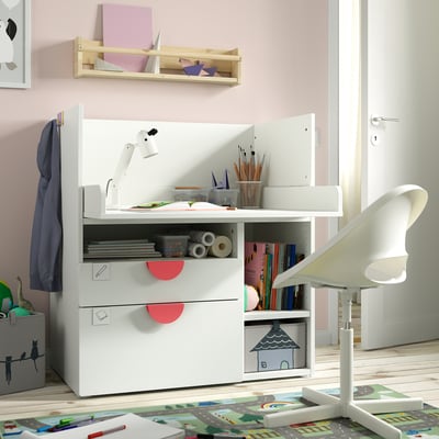 Kids white SMÅSTAD desk with pink accents, storage drawers, and shelves, next to a white chair.