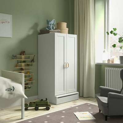 Kids room with SMÅSTAD white cabinet, toy shelf, grey rug, and grey armchair.