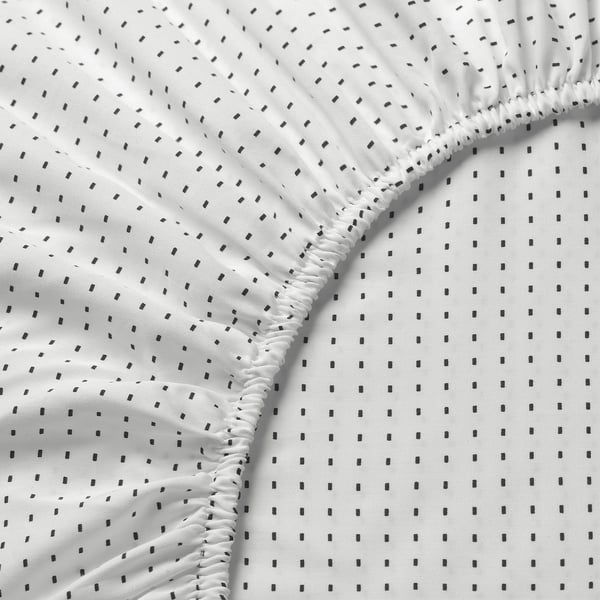 Elasticated white sheet with black dots, soft, high-quality fabric, fits mattresses up to 15 inches.
