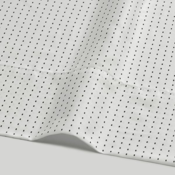 White bed sheet with small, evenly spaced black dots, neatly hemmed edges, smooth and high-quality fabric.