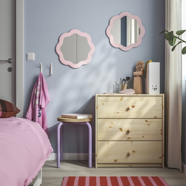 Small white wall hooks in a bedroom, ideal for hanging items, positioned near mirrors and a wooden dresser.