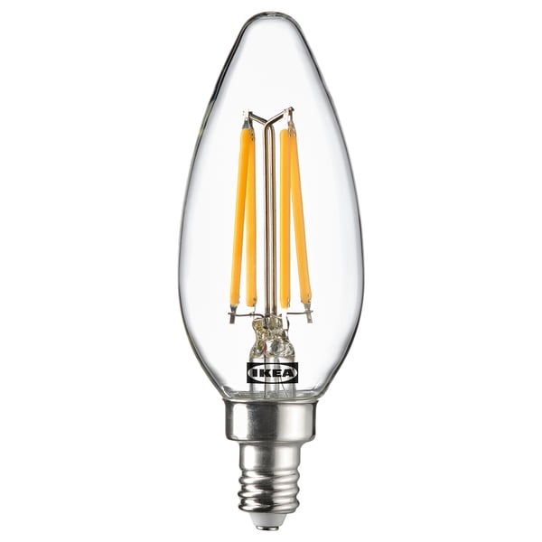 An ikea SOLHETTA led light bulb with a warm-white glow, featuring a glass cover and a classic candle shape.