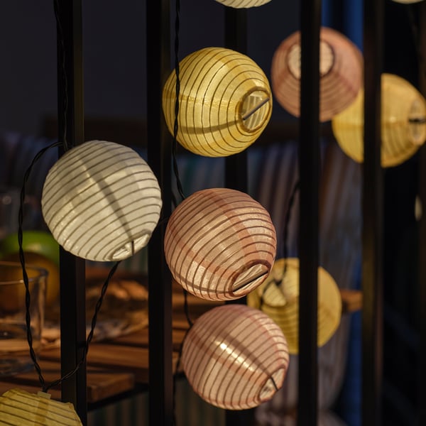 Hanging solar-powered lanterns emitting warm light in a dark setting, creating a cosy atmosphere.