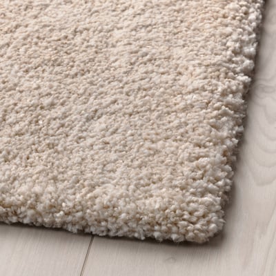 Soft, cream-colored rug with thick, plush texture, placed on wooden floor.
