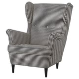 A STRANDMON chair with a black and white houndstooth pattern. It has a high, winged back and tapered legs for support.