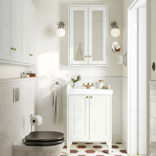 White tånnforsen bathroom vanity with bevelled panels, between wall cabinets, sink, mirror, checkerboard floor.