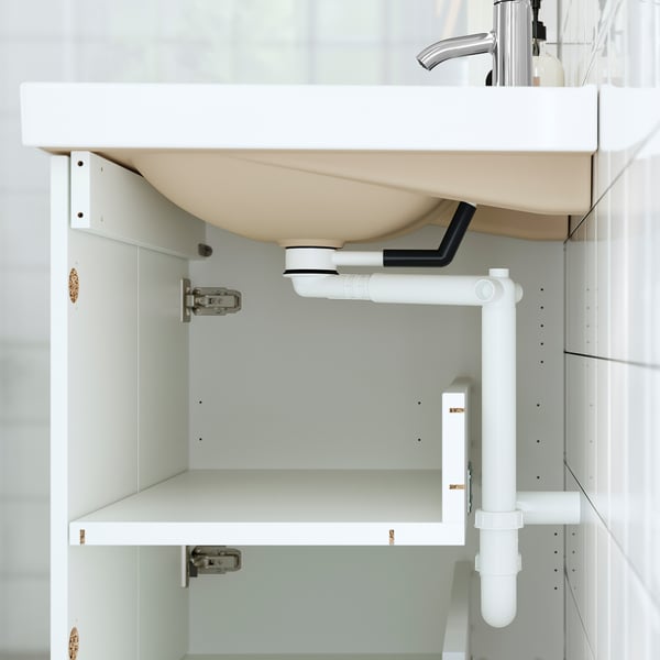 White bathroom cabinet with a curved countertop, exposed plumbing, and bevelled panels.