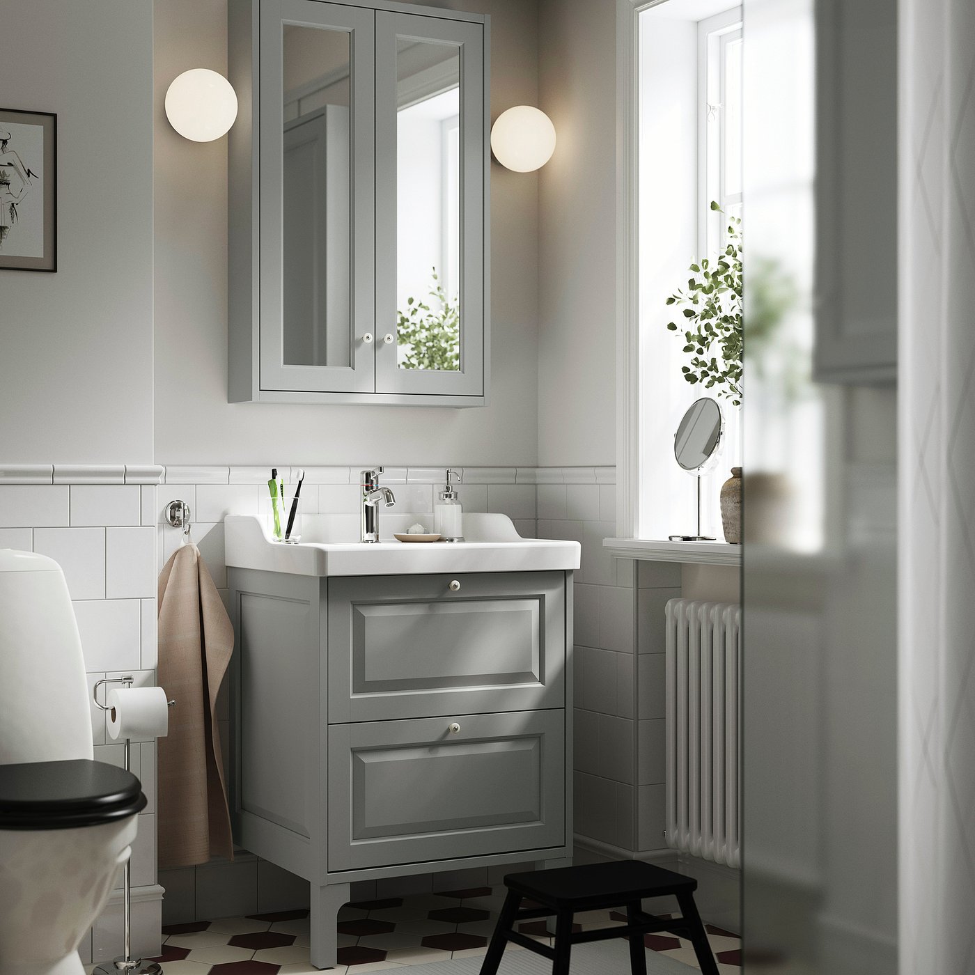 Modern grey bathroom vanity with drawers, sink, toilet, wall mirror, and black stool.