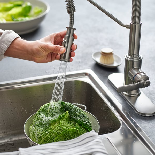 Rinsing greens in kitchen sink with pull-down tap.