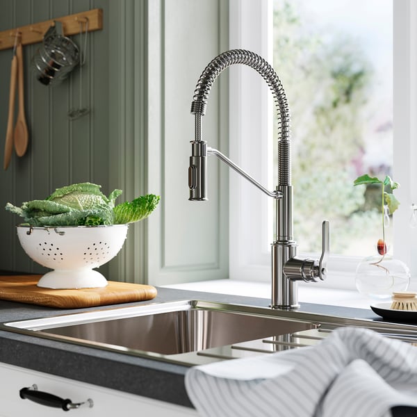 Stainless steel TAKSJÖN tap with high-arc gooseneck and pull-down sprayer in modern kitchen.