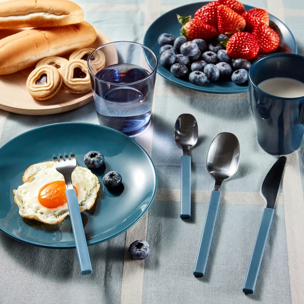 Breakfast table with bagel, berries, pastries, and juice, blue plates and cutlery.