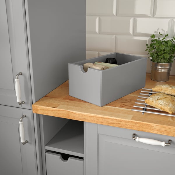 Kitchen counter with grey TORNVIKEN box containing items, placed next to cabinets.