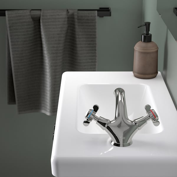 White ceramic washbasin with chrome tap and soap dispenser. The deep bowl prevents splashes and includes a drain stopper.
