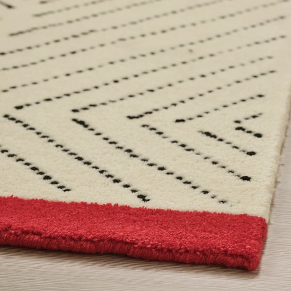 Precipice rug corner, black lines over cream, red border, soft wool texture