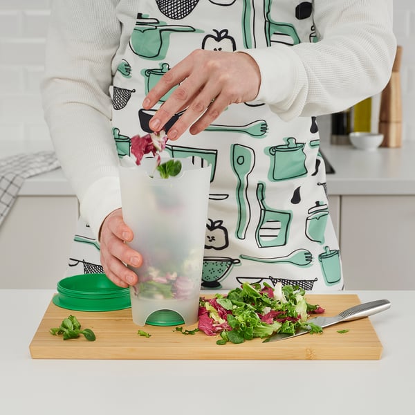 Person uses UPPFYLLD salad shaker to rinse lettuce. Easy water drainage and storage.