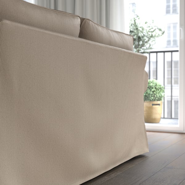 Comfy beige sofa with deep cushions in cosy room by window.