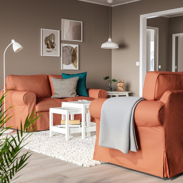 Modern living room with UPPLAND rust sofa, grey blanket, coffee table, lamp, wall art, plants.