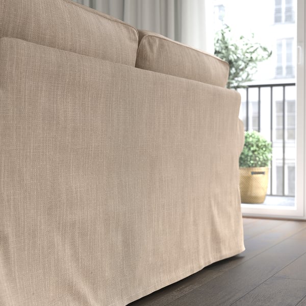 Beige UPPLAND sofa with large cushions sits near a window, offering a cosy and inviting seating area.