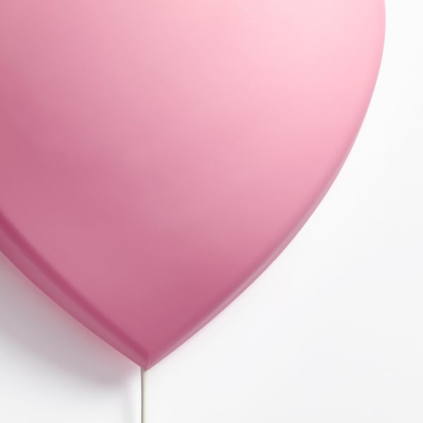 A round, smooth, light pink lamp with a soft glow, mounted on a thin rod.