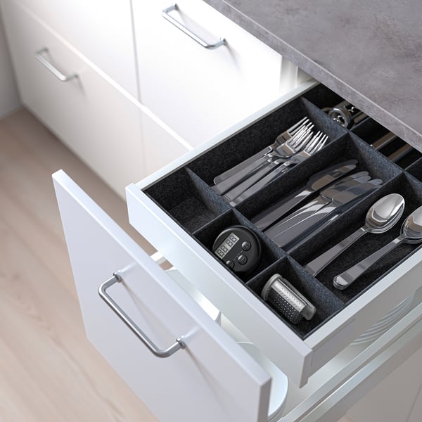 Drawer organiser for knives, forks, spoons, timer, and grater in kitchen.