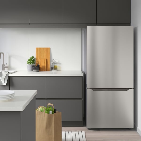 Modern kitchen with grey cabinets, white countertops, and tall stainless steel refrigerator.