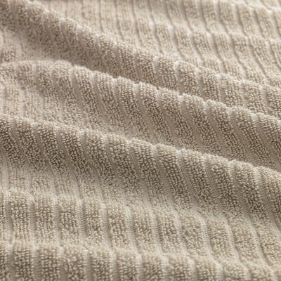 Close-up of folded beige towels, showcasing soft, absorbent cotton texture.