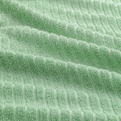 Light, soft green towel with textured rib weave, showcasing quality cotton fabric.
