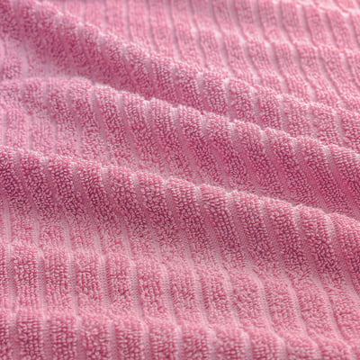 Closeup of soft pink towel, textured with fine loops, highlighting its absorbent and plush cotton quality.