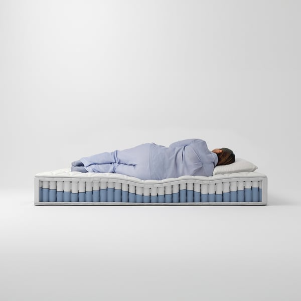 Person sleeping on blue mattress with pocket springs.