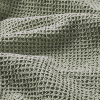 Folded green textured towel, soft fabric with waffle weave pattern.