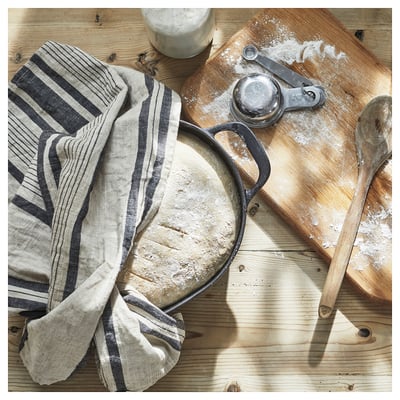 VARDAGEN cast iron pan in black, shown on wooden table with utensils.