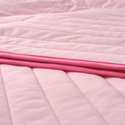 Closeup of pink recycled polyester bedspread with dark pink edge detail.