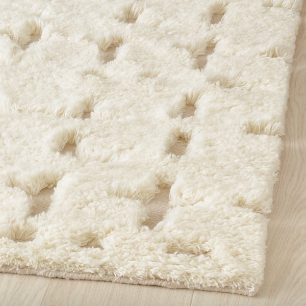 Fluffy white rug with geometric pattern, high-low pile texture, handcrafted quality.