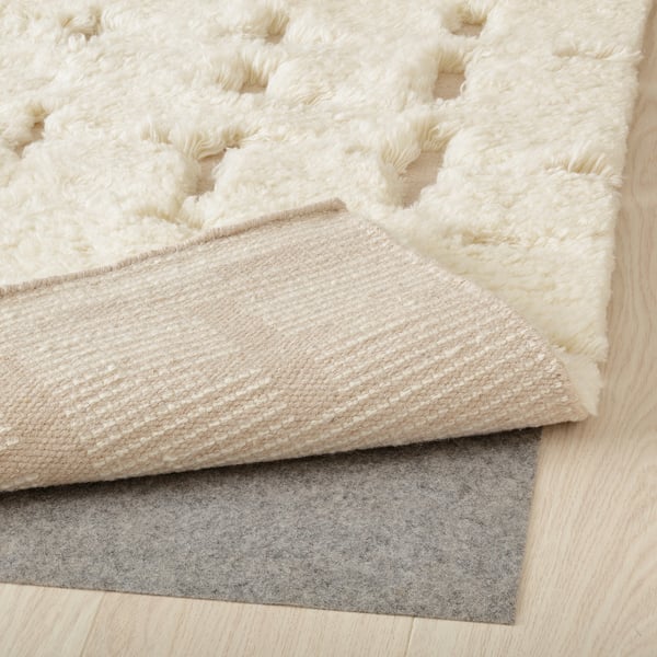 Layered rug setup: fluffy white rug on top, beige rug, and grey non-slip mat underneath.