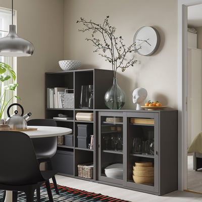 Black glass-door storage unit in dining area, holding glasses, bowls, and decorations.