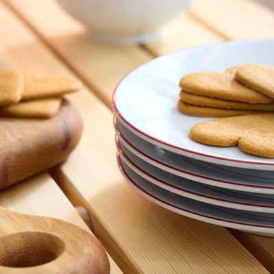 Stacked striped porcelain plates with heart-shaped cookies on top plate, set on wooden table.