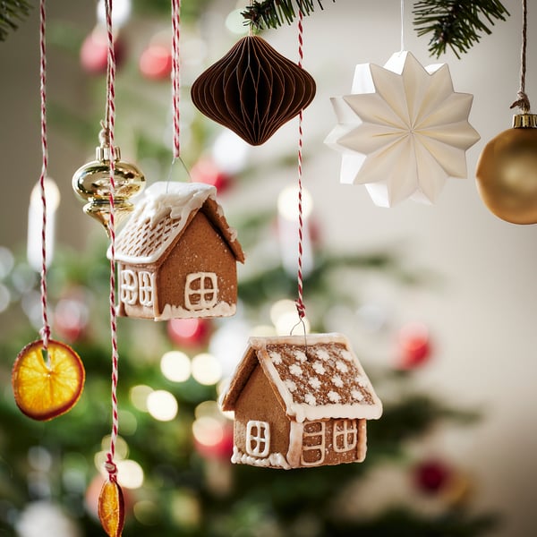 A festive christmas tree adorned with mini gingerbread houses, colourful ornaments, and dried orange slices.