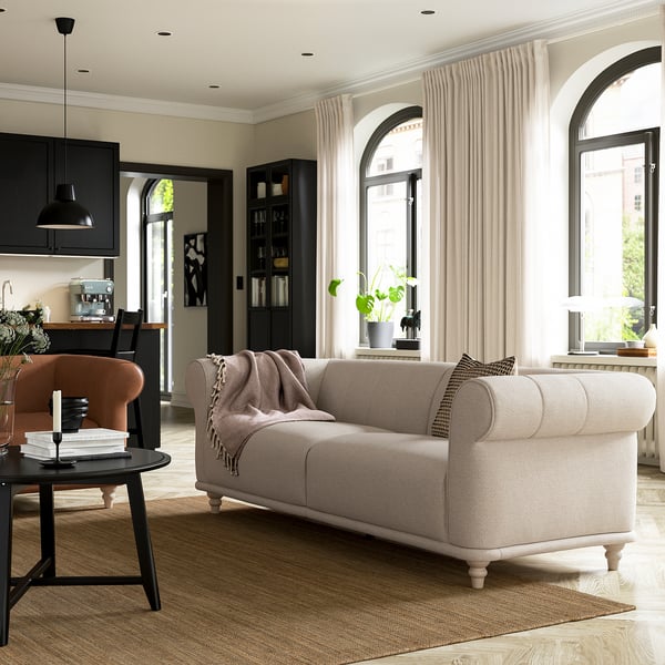 Modern living room with beige VISKAFORS sofa, wooden legs, large arched windows, black accents, and a cosy rug.